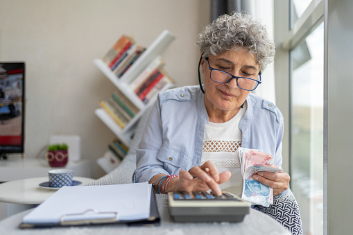 Senior Woman Counting Money And Doing Finances At Home