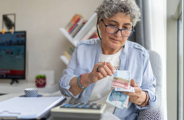 Counting Turkish Money Senior Woman Counting Money And Doing Finances At Home working seniors stock pictures, royalty-free photos & images