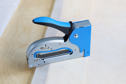 construction stapler is on surface of the material, close-up