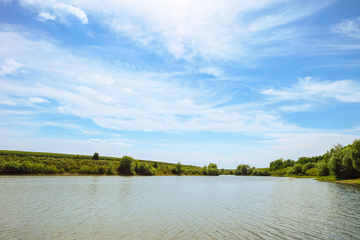 Landscape of daytime lake with blue sky and flat altostratus clouds. Belgorod region, Russia.