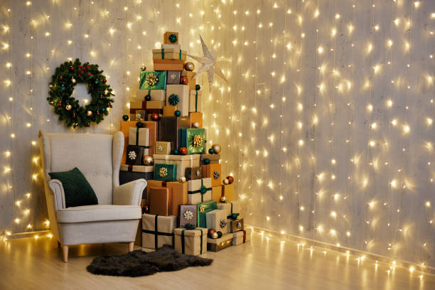 Udekorowany salon z fotelem, wieńcem i świątecznymi pudełkami ułożonymi w kształcie choinki – zdjęcie