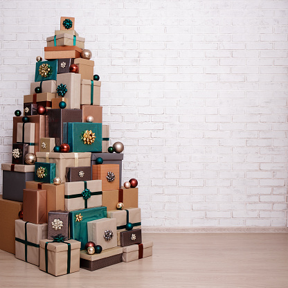 Christmas gift boxes laid out in the shape of a Christmas tree and copy space over white brick wall background