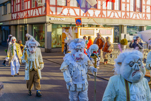 Lucerne, Switzerland - February 20, 2023: Group of participants in costumes march in the streets, and crowd, part of the Fasnacht Carnival, in Lucerne (Luzern), Switzerland