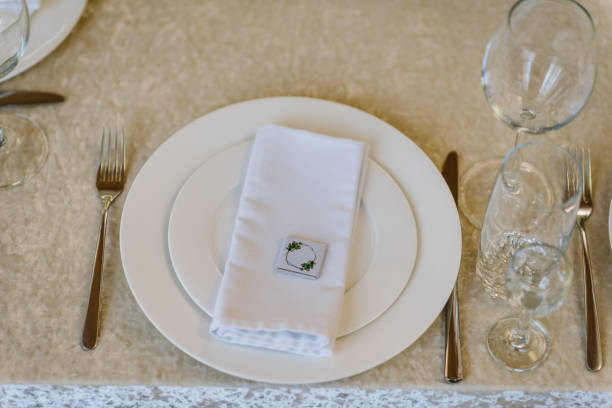 istock Serving guests, and setting table. Two plates and silverware cutlery and white linen napkin with a present gift candy. Wedding set up. Flat lay. top view. Close up. 1516560756