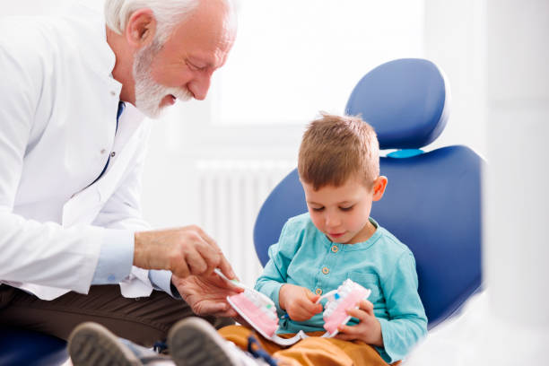istock Dentist demonstrating teeth brushing to child patient 1516565787