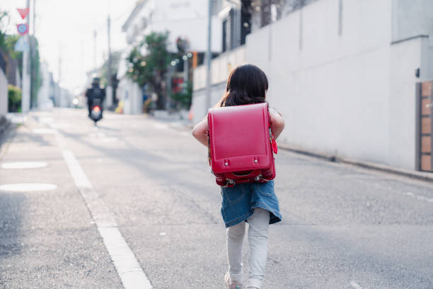 una bambina delle elementari che porta la sua borsa di scuola a scuola - randoseru foto e immagini stock