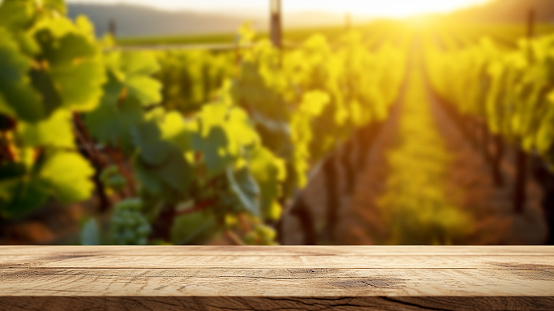 Empty wooden table top against a blurred vineyard during a beautiful sunset. Place to insert the product.