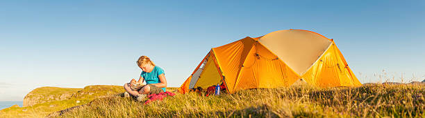 istock Idyllic summer camp child reading beside ocean cliff tent 151659937