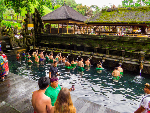 Ubud, Indonesia - February 13, 2023: People in the Holy Spring of the Tirta Empul Temple.