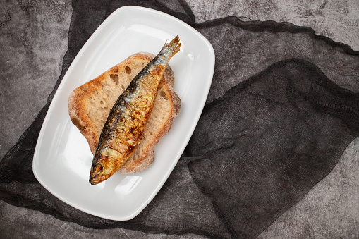 Grilled sardines with sauce on fresh bread on white dish
