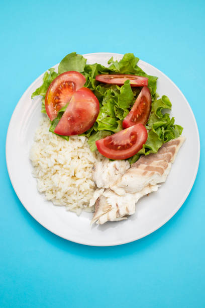 boiled fresh fish with boiled rice and fresh salad on dish