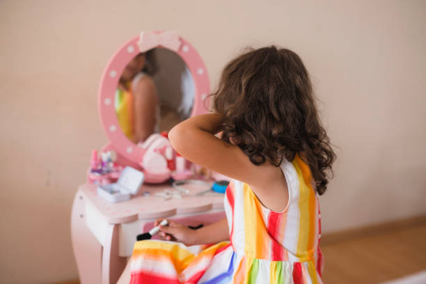 Rear view of a young girl observing herself in the mirror at home