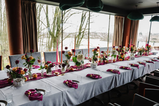 istock Luxury elegant table setting dinner with floral centerpiece in a restaurant. Decoration with orange flowers roses, candles, fruits. Plate, dishes, glasses, forks, pink napkins. Decor rustic style. 1516609474