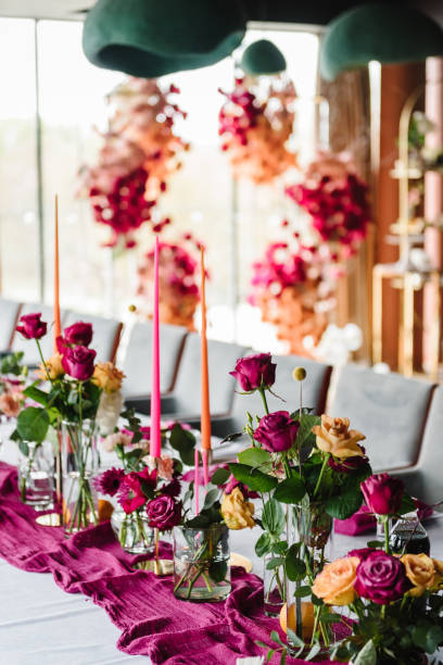 istock Luxury elegant table setting dinner with floral centerpiece in a restaurant. Decoration with orange flowers roses, candles, fruits. Plate, dishes, glasses, forks, pink napkins. Decor rustic style. 1516609479