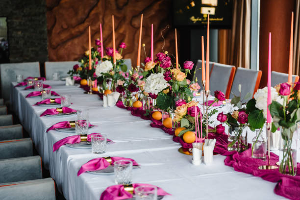 istock Luxury elegant table setting dinner with floral centerpiece in a restaurant. Decoration with pink and orange flowers roses, candles, fruits. Plate, dishes, glasses, forks, napkins. Decor rustic style. 1516609481