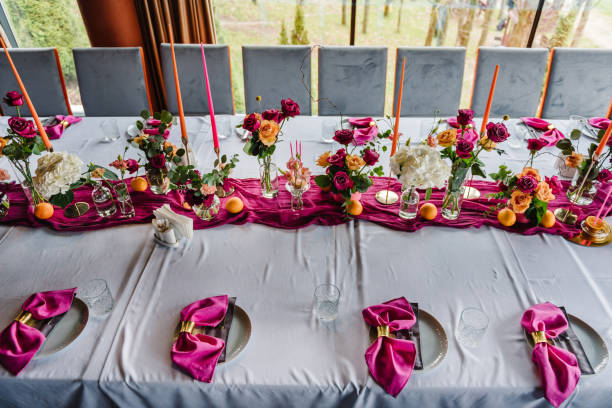 istock Luxury elegant table setting dinner with floral centerpiece in a restaurant. Decoration with orange flowers roses, candles, fruits. Plate, glasses, forks, pink napkins. Decor rustic style. Top view 1516609487