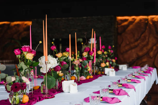 istock Beautifully organized event, served table banquet ready for guests in hall. Table set for a birthday party or wedding reception. Decoration with pink and orange flowers roses and candles and fruits. 1516609492