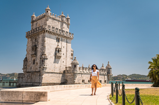Woman walking in front of Torre de Belem in Lisbon, Portugal