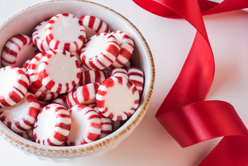 Christmas cane candy in shape of a heart. Greeting card for winter holidays, primarily Christmas with copy space. Can be used for invitations, memes, storytelling, marketing, advertising, holiday storytelling. Dark green background. Not AI