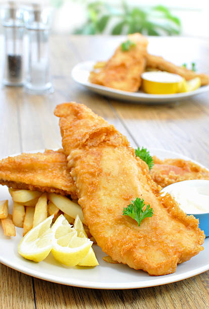 Plate of fish and chips on a wooden table stock photo