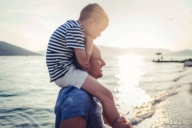 Loving dad carrying his son on his shoulders at the beach.