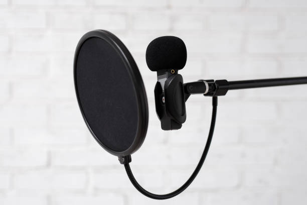 Koncepcja podcastu, nagrywania głosu i blogowania - mikrofon i filtr pop nad białą ceglaną ścianą – zdjęcie