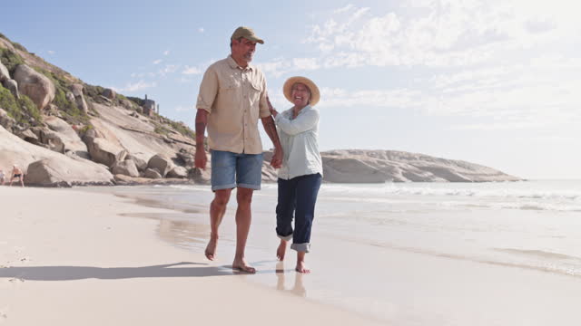 Love, beach and senior couple walking by the sea or ocean on vacation or holiday in Cape Town in conversation together. Travel, man and old woman lovers walk and talk enjoying retirement on the coast
