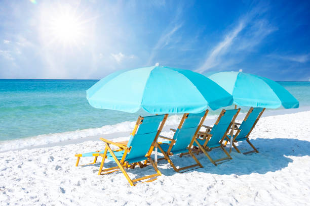 Blue Beach Chairs A group of blue beach chairs with umbrellas sitting on white sandy beaches in front of the ocean on a sunny day. clearwater stock pictures, royalty-free photos & images