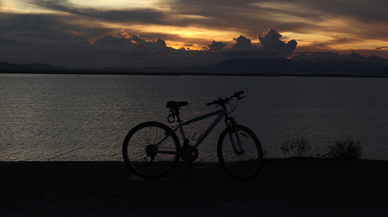 silhouette of a bicycle against the background of the sunset on the lake