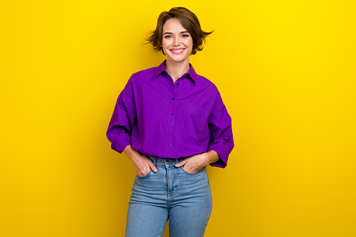 Portrait of amazing business lady wear elegant violet blouse hold hands pockets denim pants isolated yellow color background.