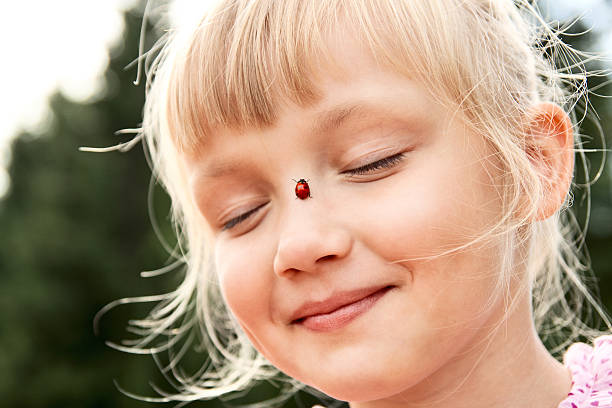 Cute little girl with ladybird on her nose