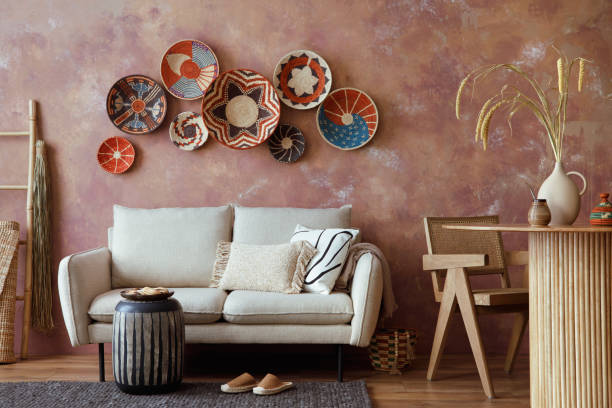 istock The stylish boho compostion at living room interior with design beige sofa, coffee table, stool wicker baskets and personal accessories. Brown and white pillows and plaid. Cozy apartment. Template. 1516720933