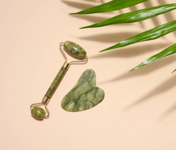 istock Green jade gouache massager and massage jade roller on a beige background, top view 1516729621