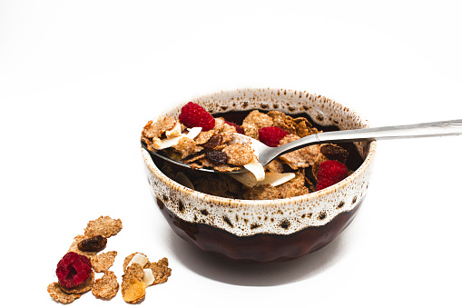 Muesli with raspberries and milk in a bowl on a white background. Healthy breakfasts, proper nutrition