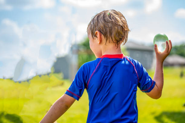 Young Caucasian boy taking aim to throw a water balloon. Young Caucasian boy taking aim to throw a water balloon. . High quality photo water balloon stock pictures, royalty-free photos & images
