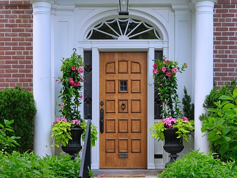 Beautiful wood grain front door of home, surrounded by flowers