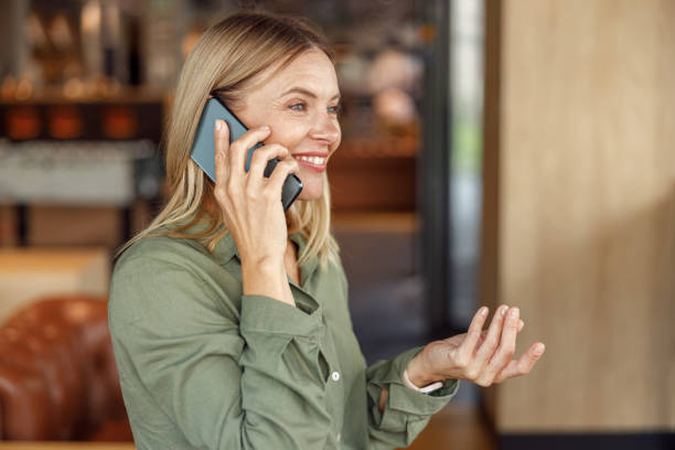 istock Smiling businesswoman is talking phone with client while standing on modern coworking background 1516749479