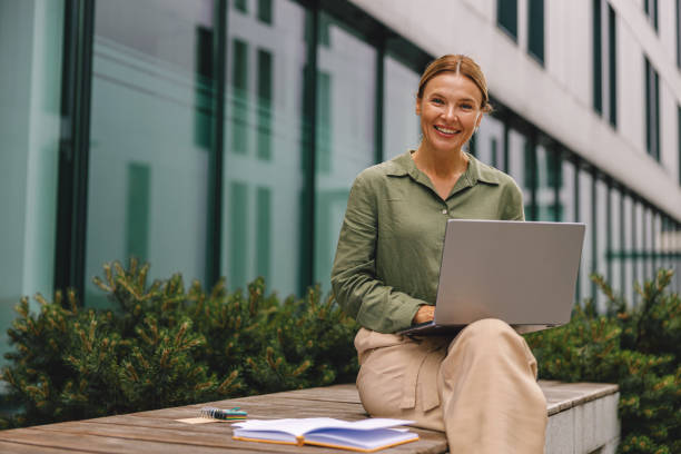 istock Woman analyst working with documents and use laptop sitting outside on modern building background 1516761398