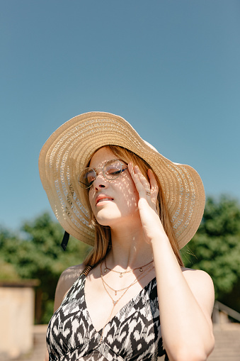 Young woman protecting herself from sun with straw hat.