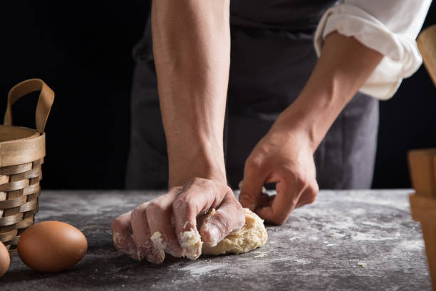 요리사는 달걀, 부엌 어두운 배경, 전문 사진 조명을 사용하여 반죽을 반죽하고 있다 - chef cooking pasta professional occupation 뉴스 사진 이미지