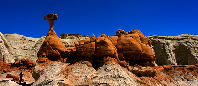 People in silhouette at Toadstool hoodoos in the Southwest with red sandstone and blue sky in wilderness