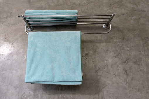 Blue towel is hanging on hanger in resort restroom or toilet prepared for guests.