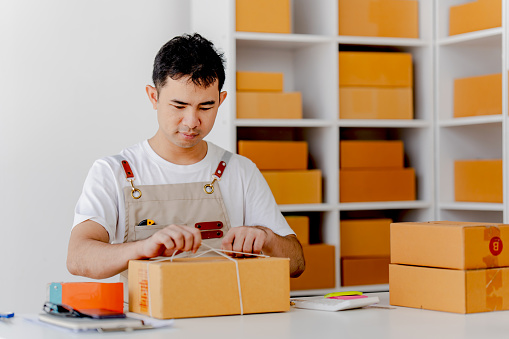 Small male SME start-up businessman, inspecting parcels at work, freelancer, salesman, checking production orders Packing products for delivery to customers, SME concept