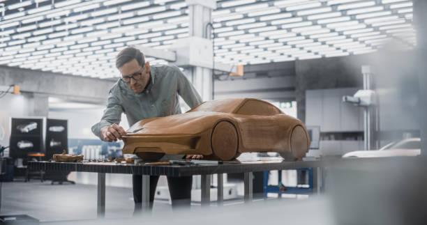 istock Car Modeler In Creative Workplace Working on a Concept Car Made Out of Plasticine Modeling Clay. Handsome Designer Using Spatula to Smooth the Prototype Model of a Modern Electric Sportscar 1516854658