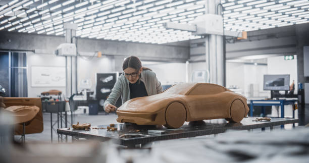 istock Car Modeler in Creative Workplace Working on a Concept Car Made Out of Plasticine Modeling Clay. Female Designer Using Spatula to Smooth the Prototype Model of a Modern Electric Sportscar 1516855186