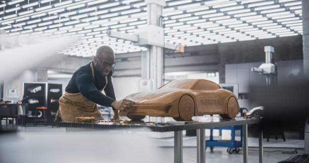 diversi artisti automobilistici africani che fanno gli ultimi colpi sulla sua ultima creazione di concept car. designer nero al lavoro su un nuovo prototipo, scolpendo il modello 3d industrial plastilina clay di una coupé sportiva. - automobile personale foto e immagini stock