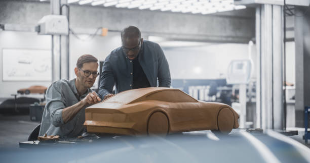 istock Enthusiastic Teamwork of Two Diverse Creative Colleagues Working in an Automotive Development Design Agency. Professional Sculptor Working Together with an Engineer, Discussing the Prototype Vehicle 1516859480