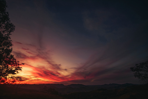 An image capturing the transformation of the sky, with orange clouds contrasting against the nighttime blue during a beautiful sunset. The scene conveys a sense of transition and mystery, offering a fascinating glimpse into the ephemeral beauty of the twilight hour.