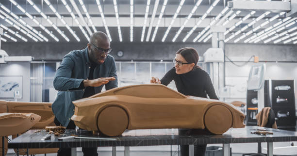 istock Enthusiastic Teamwork of Two Diverse Creative Colleagues Working in an Automotive Development Design Agency. Professional Sculptor Working Together with an Engineer, Discussing Prototype Vehicle 1516863312
