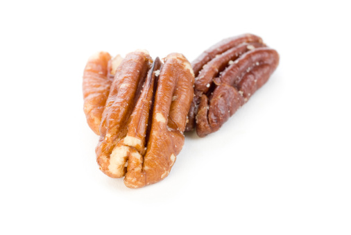 Three shelled pecans on a white background. 
